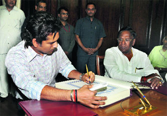 Sachin Tendulkar signs the oath book as Minister of State for Parliamentary Affairs V. Narayanasamy watches during the swearing-in ceremony at Parliament in New Delhi on Monday.