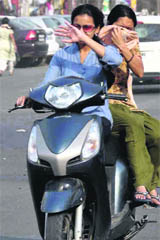 Two girls cover their faces to save themselves from dusty winds that hit Haridwar city.