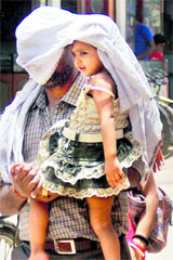 A man protects himself and his kid from scorching heat as temperature soars in Varanasi on Monday. 
