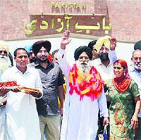 Surjeet Singh flanked by his son Kulwinder Singh (left) and daughter Parminder Kaur (right) waves after stepping onto the Indian soil at Attari border on Thursday.