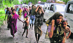 Residents of Dimol village leave their homes following ethnic clashes in Kokrajhar district on Tuesday.  PTI