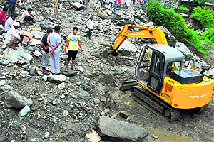 An earth mover clears the Badrinath highway after slides in Chamoli in Uttarakhand