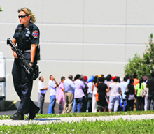 A cop stands guard as bystanders gather at the scene of shooting at a gurdwara in Oak Creek, US, on Sunday.