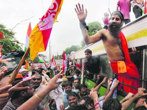 Ramdev waves to his supporters as he is taken away in a bus after being detained by the police on Monday. 
