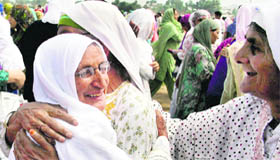 A girl takes a picture of devotees offering prayers at an Eidgah in Srinagar.