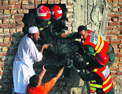 Rescue workers and residents recover a body from a building after a fire at a shoe factory in Pakistan.