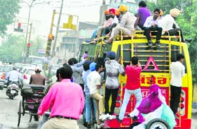 Passengers risk their lives by travelling on the roof of an overloaded bus in Ludhiana.