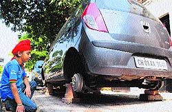 A boy looks at a car without its wheels, which were stolen, at Sector 44