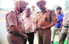 SSP Hardyal Singh Mann inspects a pistol at a check post in Doraha