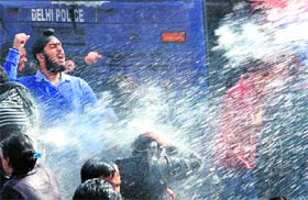Demonstrators face a water cannon during a protest demanding safety for women at Vijay Chowk in New Delhi on Saturday