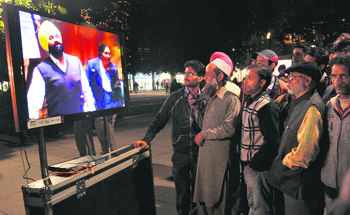 People viewing a recording of the Vidhan Sabha proceedings on a screen put up by the Congress in a marketplace in Chandigarh.