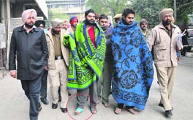 Maninder Pal Singh Johar, alias Sunny Goodwill (with a bandaged foot), and his nephew Aman being taken to a court in Ludhiana on Thursday