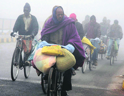 People ride bicycles in fog in Allahabad on Saturday.