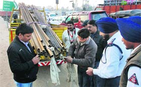 Traffic policemen direct a driver to tie cloth on the rear of the iron rods loaded on a truck during Traffic Week — 2013 at Zirakpur on Thursday.