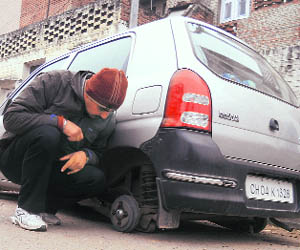 A boy seems confused that how thieves manged to remove all the tyres of an Alto in Sector 44, Chandigarh on Monday.