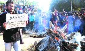 A student holds a placard demanding justice for the Delhi gang rape victim, as students dance to the tune of controversial songs of Punjabi singer Honey Singh during the Lohri celebrations at the Student Centre, Panjab University, in Chandigarh on Monday