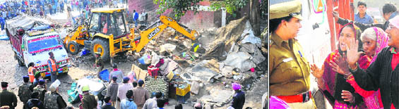 An earthmoving machine demolishes illegal structures during an anti-encroachment drive at the Sector 26 Grain Market in Chandigarh on Wednesday; (right) Protesters argue with a policewoman.