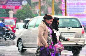 Walking in the rain: Women walk on a busy road as it rains in Ludhiana on Friday.