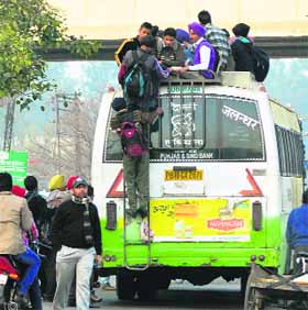 Students risk their lives by travelling on the rooftop of an overloaded bus in Ludhiana on Thursday.