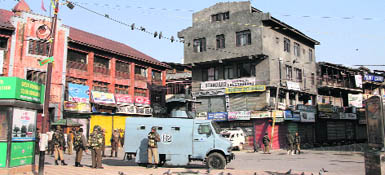 CRPF soldiers stand guard on a deserted street in Srinagar during curfew on Saturday. 