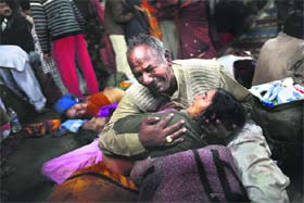 A man weeps as he holds his wifes body on the platform in Allahabad on Sunday