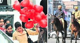 Girls walk past balloons at a busy market; and (right) policemen patrol a street on Valentine’s Day in Ludhiana on Thursday