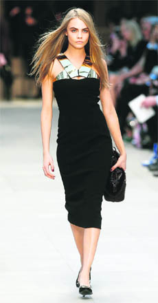 Model Cara Delevingne presents a creation from the Burberry Prorsum Autumn/Winter 2013 collection during London Fashion Week.