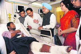 PM Manmohan Singh and AP CM Kiran Kumar Reddy (C) talk to a blast victim in Hyderabad on Sunday
