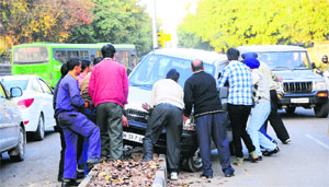 Passers-by push a car that crashed into a divider on the road separating Sectors 7 and 8 in Chandigarh on Tuesday.
