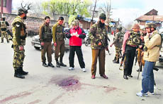 Paramilitary forces inspect the spot where militants opened fire on a police party in a busy market in Sopore district on Sunday.