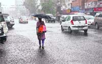 A woman braves a sharp shower in Kochi on Saturday