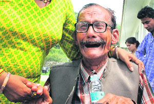 An elderly pilgrim is consoled by a relative after being rescued from the upper reaches.
