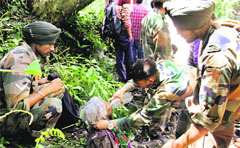 Army jawans offer water to an old woman on a hillside during rescue operations in Uttarkashi on Saturday.