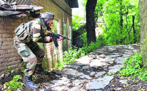 A jawan takes position near the house where militants were holed up at Tral in Pulwama on Monday. 