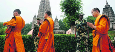 Security personnel stand guard as monks walk past at the Mahabodhi temple complex in Bodh Gaya on Monday. 