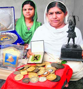 Salinder Kaur, wife of Makhan Singh, with the medals and trophies won by him. Her daughter-in-law Manpreet Kaur is also in the picture