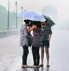 Young girls with their umbrellas at Rajpath during heavy rains in New Delhi on Sunday.