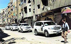 A Free Syrian Army fighter passes by the convoy of vehicles carrying a team of UN chemical weapons experts in Damascus