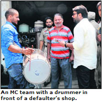 An MC team with a drummer in front of a defaulters shop.