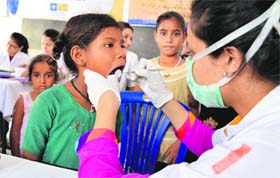 A doctor examines the teeth of a child during a dental check-up camp at Government Primary and High School, Ambedkar Nagar, Model Town Extension
