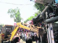 A JCB machine removes encroachments from Paltan Bazaar in Dehradun on Saturday.