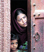 A mother and daughter peek from inside their house in Muzaffarnagar on Tuesday