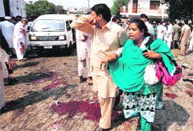 A man and woman mourn the death of their relatives at the site of a blast at a church in Peshawar on Sunday