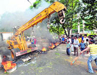 Protesters stop a crane as they block a road with burning tyres at Vizag.