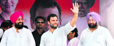 Rahul Gandhi waves to the crowd as party leaders Amarinder Singh and Partap Singh Bajwa look on.
