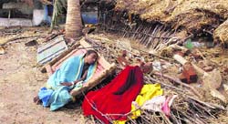 A woman rests near her damaged house in Podampeta village in Ganjam district of Odisha on Sunday.