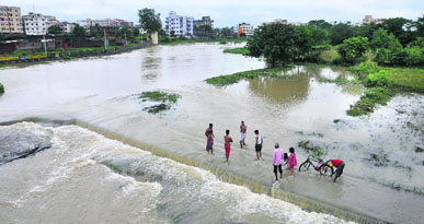 Villagers stand in the overflowing Swarnrekha river in Ranchi on Monday.