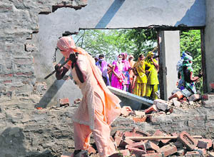 A woman smashes a police post at Lalupura village in Karnal on Tuesday. 