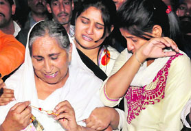 Sarabjit Singh's family members weep as they look at his belongings received from Pakistan at Bhikhiwind, near Amritsar