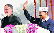 AAP leader Arvind Kejriwal acknowledges supporters while Lt Governor Najeeb Jung looks on in New Delhi on Saturday. Kejriwal was sworn in as Delhis seventh CM